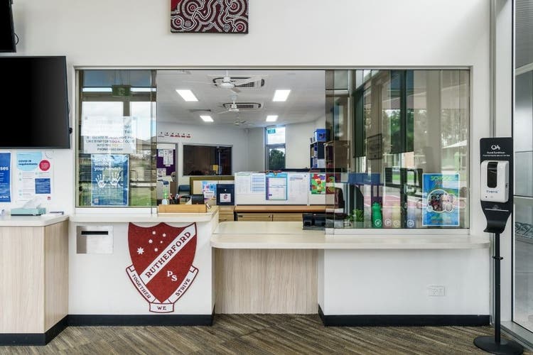 The internal area of the school administaion foyer area showing the front desk with the school logo below it.