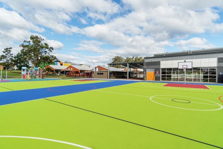 Brightly coloured basketball courts with the hall in the background.