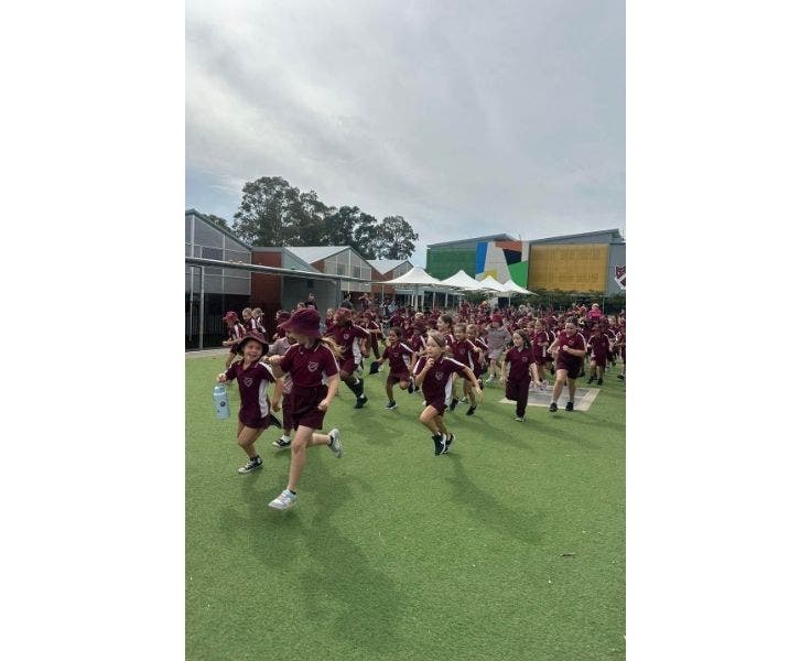 A large group of students run down the common area at the start of the cross-country race.